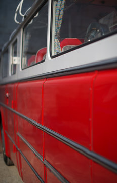 Part of red retro bus with passenger seats.