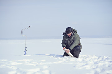Fototapeta na wymiar Fisherman in winter on the ice caught fish.