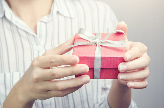 Closeup, Hand holding red gift box, female giving gift, New year holidays and greeting season concept.