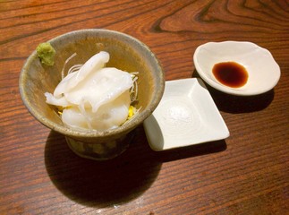 Slices of japanese octopus in a bowl with salt and soy sauce