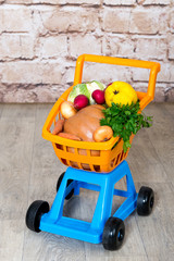 Children's plastic trolley filled with fruits and vegetables. Going shopping in the supermarket or on the market.
