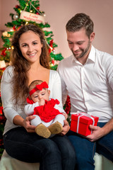 Obraz na płótnie Canvas Junge glückliche Familie vor dem Christbaum - Weihnachten