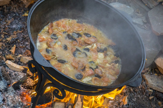 Cooking meat on a fire in cast-iron cauldron.