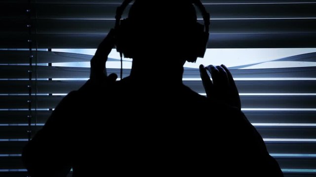 silhouette guy wiretapping and pulling down metal window blinds to spy on his neighbor