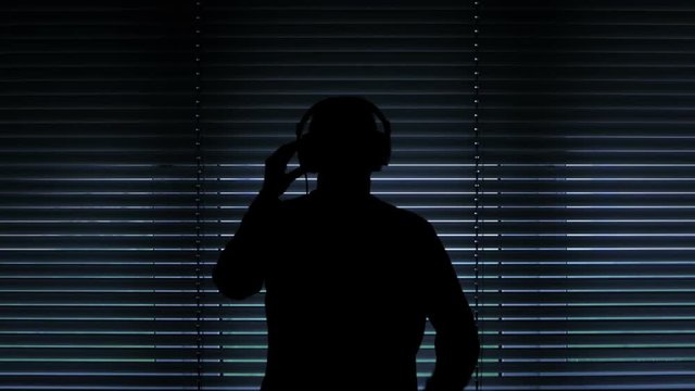 silhouette guy wiretapping and pulling down metal window blinds to spy on his neighbor