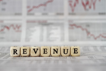 Revenue built with letter cubes on newspaper background
