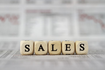Sales word built with letter cubes on newspaper background