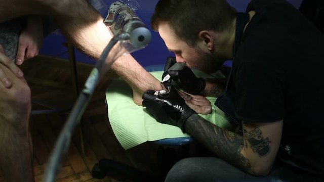 Uder lamp master makes a tattoo