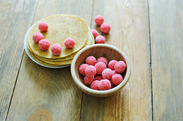 Cup with a pink round candy dish with pancakes on wooden background. Carnival.
