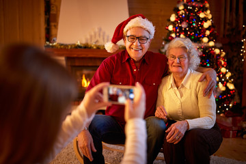girl with smartphone taking picture grandparents on Christmas .