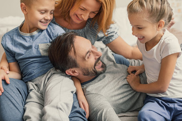 Happy family lying down on bed at home