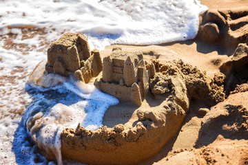 waves wash away sand castles on beach the sea