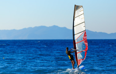 Recreational Water Sports. Windsurfing. Windsurfer Surfing The Wind On Waves In Ocean, Sea. Extreme Sport Action.  Sporting Activity. Healthy Active Lifestyle. Summer Fun Adventure. Hobby © vladimircaribb