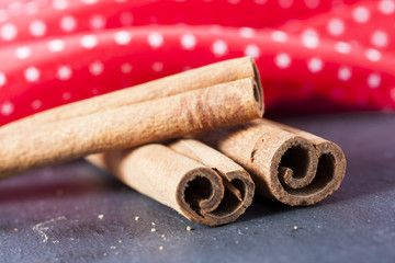 Cinnamon sticks close up on stone  table with red background.