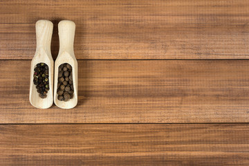 Wooden shovels with black peppercorn and allspice. Top view.