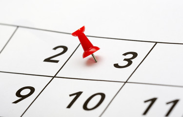 Pin on the date. The third day of the month is marked with a red thumbtack. Focus point on the red pin.