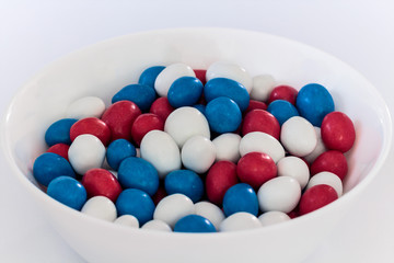 White bowl with red, white and blue peanut filled chocolate candy  .