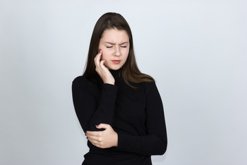 Portrait of a pretty woman having toothache  standing over gray background