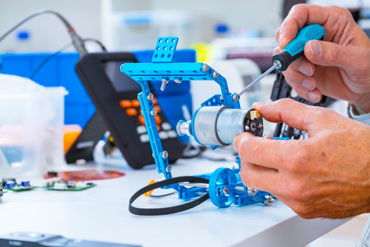 Robotics development closeup. Electronics engineer or programmer hands with special tools working with robot arm. Modern technologies. DIY Hobby Concept