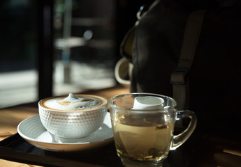A cup of coffee and a cup of tea on the wood table.