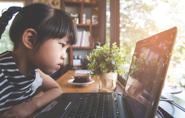 Technology and early education. Child use laptop for fun and learning. Boy sit alone with computer cafe