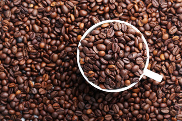 Brown roasted coffee beans in white cup