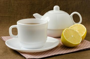 on napkin cup of tea with lemon in saucer and teapot