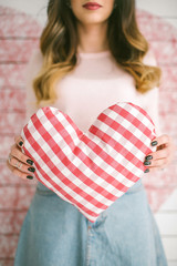 Young beautiful woman holds heart-shaped pillow in decorated stu
