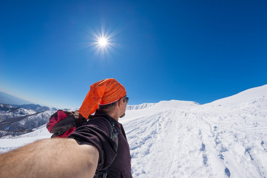 Adult alpin skier with beard, sunglasses and hat, taking selfie on snowy slope in the beautiful italian Alps with clear blue sky. Wanderlust and adventures on the mountain. Wide angle fisheye lens.