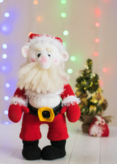 Knitted toy Santa Claus on a background of colorful bokeh.