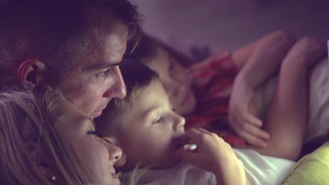 Happy family watching movie on tablet pc in a dark room. Full HD 1080p, slow motion 240 fps