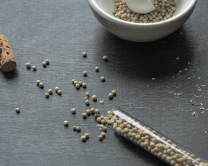 White pepper scattered on a table and mortar with pepper

