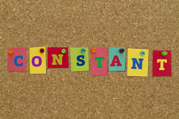 Constant word written on colorful sticky notes pinned on cork board.