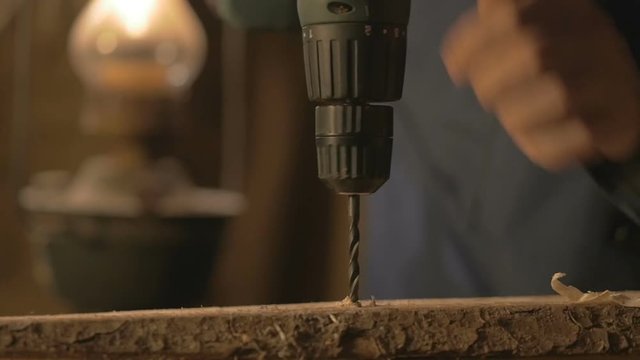 The carpenter makes a hole in the Board drill. master works in the Studio tool.