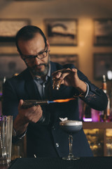 Barman is making cocktail at night club.