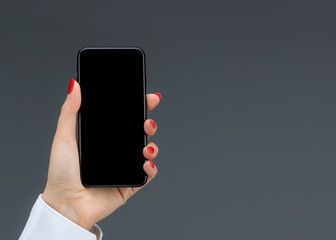 Hand holding mobile smart phone isolated on a gray background