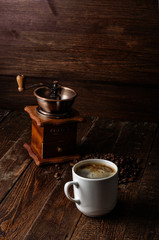 Coffee cup with coffee mill on dark wood background