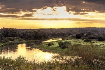 Fototapeta na wymiar Vibrant sunrise with beautiful rural landscape at river bank with moody sky and sunlight