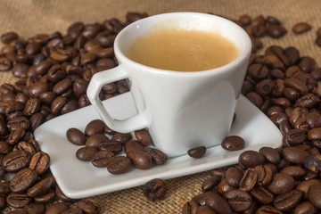 Cup and grain of coffee over textile background