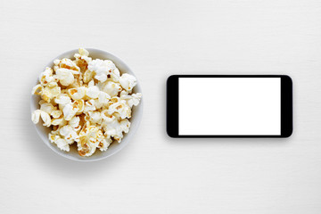 Popcorn and smartphone on white table