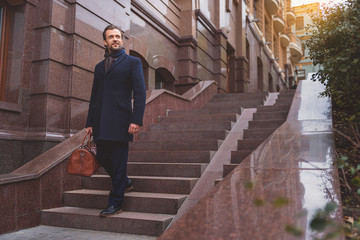 Successful businessman on staircase with suitcase