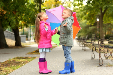 Cute children with umbrella in park