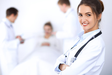 Fototapeta premium Female doctor smiling on the background with patient in the bed