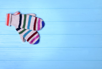 Pair of colorful knitted mittens on blue wooden background