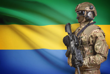 Soldier in helmet holding machine gun with flag on background series - Gabon