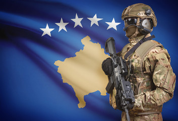 Soldier in helmet holding machine gun with flag on background series - Kosovo