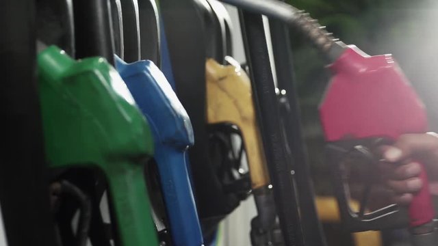 Gasoline or petrol station gas fuel pump nozzle. Filling station. Close-up of a men's hand using a fuel nozzles at a gas station.