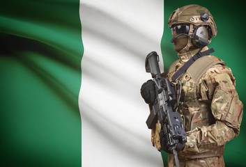 Soldier in helmet holding machine gun with flag on background series - Nigeria
