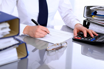 Bookkeeper or female financial inspector  making report, calculating or checking balance. Internal Revenue Service checking financial document. Audit concept.