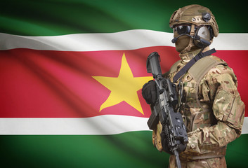 Soldier in helmet holding machine gun with flag on background series - Suriname